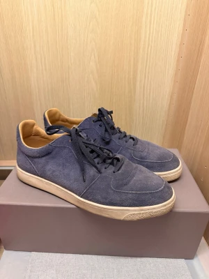 Brunello Cucinelli Low Top Suede SneakerBrunello Cucinelli Low Top Suede Sneaker - Brunello Cucinelli Blue Suede Low Top Sneaker, strl 44.  Nypris: 995 USD (motsvarande cirka 10 500 kr).  Exklusiva italienska sneakers i marinblå mocka med originalkartong. Använda men i fint skick.  Säljs då de inte kommer till användning längre.