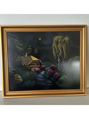 Japansk Tavla med nattligt landskap i guldram, 55x46cm - Inbjudande handmålad japansk tavla med motiv av en stuga vid en flod omgiven av träd under en månbelyst natt. Målningen har detaljer i gult, rosa och grönt som framhävs mot den mörka bakgrunden. Inramad i en klassisk guldfärgad ram av trä. Mått 55x46cm. Olja på trä. Mycket gott skick, som ny!