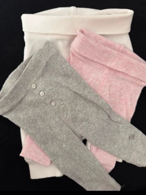 3-pack leggings för baby, ekologisk bomul - Säljer ett 3-pack mjuka leggings för baby från Åhléns i storlek 44,50. Färgerna är ljusgrå, ljusrosa och vit. Alla leggings har bred mudd i midjan och är tillverkade i ekologisk bomull. De grå har knappar framtill för extra detalj.