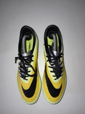 Nike Hypervenom gula fotbollsskor - Säljer ett par Nike Hypervenom fotbollsskor i gult och svart med klassisk Nike-logga. Skorna har snörning, låg profil och ovandel i syntetmaterial för bra bollkontroll. Perfekta för dig som vill sticka ut på planen med stilrena och sportiga skor. 