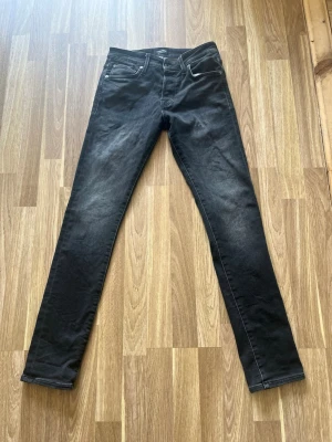 Svarta slim fit jeans 28/32 - Säljer ett par svarta slim fit jeans med klassisk femficksdesign. Jeansen har en snygg tvättad look och är tillverkade i stretchigt denimtyg för skön passform. Perfekta till en avslappnad stil.