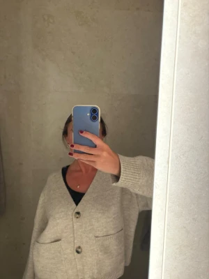 Beige oversized kofta med fickor - Mysig beige oversized kofta med stora knappar framtill och två rymliga fickor. Koftan har långa ärmar och ribbade muddar vid ärmslut och nederkant. Perfekt för lager på lager och chill stil.