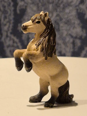 Schleich häst  - Säljer en schleich häst beige kropp och mörkbrun man och svans. Hästen står på bakbenen och har detaljerade drag i ansiktet och benen. 