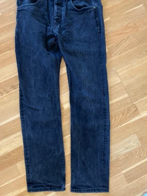 Mörkblå raka jeans - Snygga mörkblå jeans med rak passform och klassisk femficksdesign. Jeansen har diskreta slitningar och är tillverkade i denim. Perfekta för en avslappnad och stilren look.