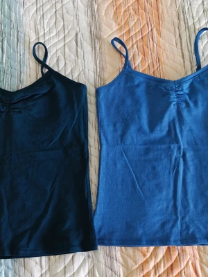 Blå och grön  linnetoppar InWear - Två stilrena linnetoppar från InWear Essentials i blått och grönt. Båda har smala axelband och lätt rynkdetalj vid halsen. De är gjorda i mjuk bomull och har en enkel, slim passform som är perfekt för att matcha med jeans eller kjol.Pris 50 SEK per styck 