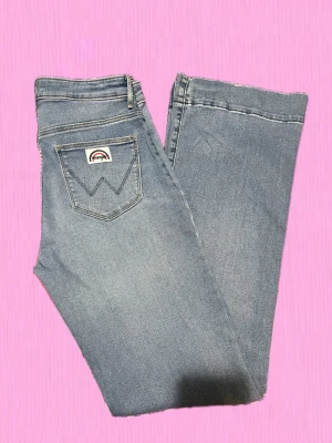 Wrangler ljusblå raka jeans W28 L32 - Ljusblå jeans från Wrangler med klassisk femficksdesign och raka ben. Jeansen har en tydlig logga på bakfickan och är tillverkade i denim. Perfekta för en avslappnad och trendig look.