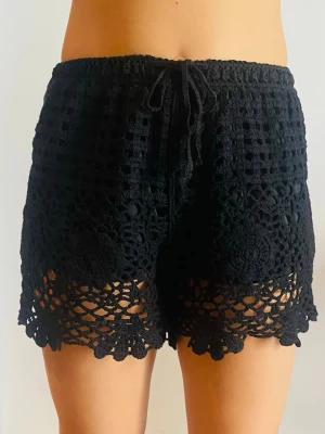 Svarta virkade shorts med snörning - Svarta virkade shorts med snyggt mönster och snörning i midjan. De har en lös passform och fina virkade detaljer längs benen. Perfekta för sommaren och ger en chill vibe till din outfit.