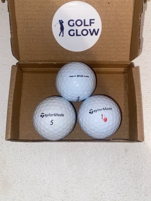 TaylorMade T5P vita 3-pack - Tre vita golfbollar från TaylorMade i en enkel kartong med Golf Glow-sticker. Bollarna har siffrorna 1 och 5 tryckta på sig och klassisk dimpled yta för bättre flyg. Perfekt för golfare som vill ha kvalitetsbollar.