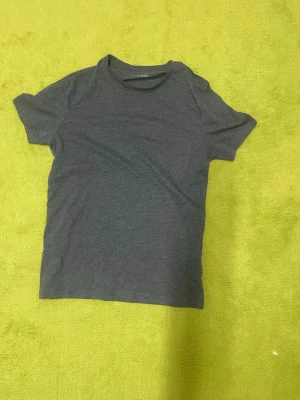 Mörkgrå basic t-shirt - En enkel och stilren mörkgrå t-shirt med rund hals och korta ärmar. Perfekt till jeans eller shorts för en clean look. Tillverkad i mjuk bomull som känns skön mot huden.