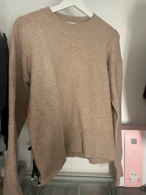 Beige stickad tröja & Other Stories - Mysig beige stickad tröja från & Other Stories Paris Atelier. Tröjan har rund halsringning, långa ärmar och bred ribbstickad kant nedtill och vid ärmsluten. Perfekt för lager-på-lager och enkel att matcha med jeans eller kjol. Bara använd ett få tals gånger så typ som nyskick💞