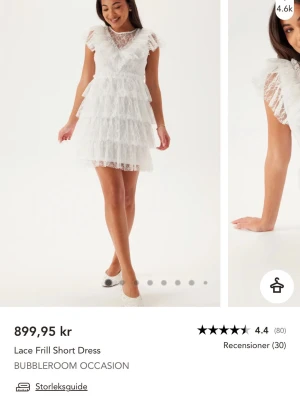 Vit spetsklänning från Bubbleroom - Söt vit klänning i spets från Bubbleroom med korta ärmar och hög hals. Klänningen har volangdetaljer, genombrutna spetsdetaljer och en figursydd midja. Knäpps baktill med pärlknappar(se bild)  Använts en gång på en skolavslutning 💕