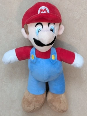 Super Mario mjukisdjur - Säljer ett mjukisdjur som föreställer Super Mario från Nintendo. Gosedjuret har röd keps med ett vitt M, blå hängselbyxor, röd tröja, vita handskar och bruna skor. Perfekt för dig som gillar spel eller vill ha en rolig inredningsdetalj. Längd ca 23 cm 