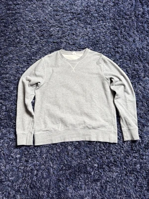 Arket sweatshirt - En stilren grå sweatshirt med rund halsringning och ribbade muddar vid ärmslut och nederkant. Tröjan har en klassisk passform och är tillverkad i mjukt sweatshirtmaterial, perfekt för en avslappnad look. Den är lite mindre i passformen än en vanligt S, hör av er vid minsta fundering!