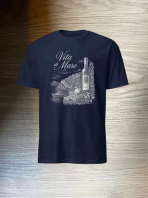 Svart t-shirt med Vita di Mare-tryck - Snygg svart t-shirt med ett stort tryck framtill som föreställer en vinflaska, frukt och texten 'Vita di Mare'. Perfekt för dig som gillar stilrena motiv med italiensk känsla. Klassisk passform och rund hals. Riktigt fräsch till sommaren kom om du har minsta lilla fråga 