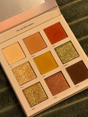 LH cosmetics Creator ögonskuggspalett - Säljer en Creator ögonskuggspalett från LH cosmetics med nio olika nyanser i både matta och skimrande toner. Färgerna sträcker sig från beige, brunt och gult till grönt och koppar. Paletten har fyrkantiga pans och kommer i en stilren, ljusrosa förpackning. Bara swatchad. 