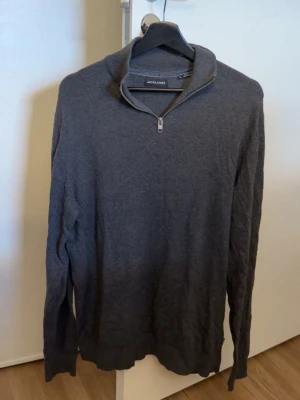 Mörkgrå stickad tröja  - Mörkgrå stickad tröja från Jack & Jones med halv dragkedja och hög krage. Jättefint skick. 