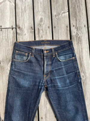 Mörkblå nudie jeans grim Tim  - Mörkblåa jeans från nudie jeans i modellen grim Tim och storleken 31/32. Nypris över 1600 medans jag säljer de för endast 599kr. Hör gärna av er vid intresse eller frågor!