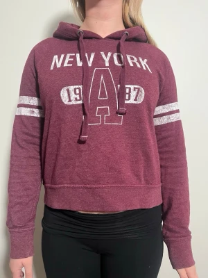 Aéropostale vintage hoodie  - En vin röd vintage hoodie med en retro look från märket Aéropostale. Hoodien har ett vitt tryck framtill. OBS den är unisex. OBS size M men är mer som S-Xs i herr storlek. Modellen är 164 och tjej.