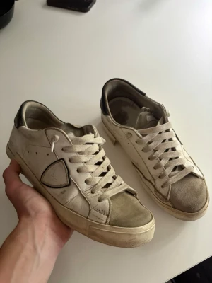 Philippe Model strl 41 - Snygga vita sneakers från Philippe Model med beige mockadetaljer på tån och svart hälparti. Självklart äkta har sätt bättre dagar men funkar nog att limas lite så är de som nya har nog vart så här ett bra tag nu och inget jag bryr mig om. Box medföljer 