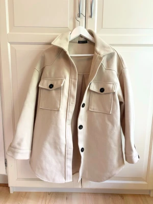 Beige skjortjacka  - Sparsamt använd, mycket fint skick. Skärpet till jackan ingår inte, men går utmärkt att använda den utan eller sätta dit ett eget skärp.