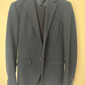 Tiger Kavaj kostym - Fin kavaj använd en enstaka gång, i tygmaterial. Storlek 46. Hämtas i Nacka Strand, frakt ingår inte i priset.