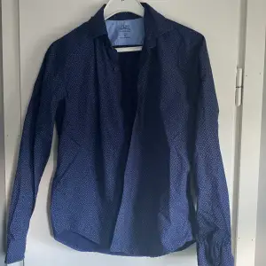 Nyskick. Marinblå skjorta med diskret mönster. Detaljfoto taget så mönstret syns