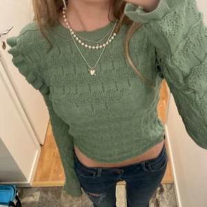 Stickad tröja med volanger - Bra skick dock ett igensytt hål på underarmen (bild 2) men det syns inte när man har på sig den!