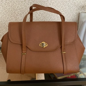 Handväska  - Köpt begagnat men kom aldrig till användning då det inte är min stil. Remmarna har jag lagat så de har delvis ljusare stygn (försvinner nog med användning). Väskan har även fläckvis några missfärgningar men de märks knappt (exempel i bild 5)