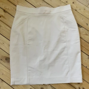 Pennkjol/kostymkjol - Jättefin crémefärgad kjol från H&M. Storlek 40. Tunn underkjol på insidan. Använd fåtal gånger. Jättefint skick!
