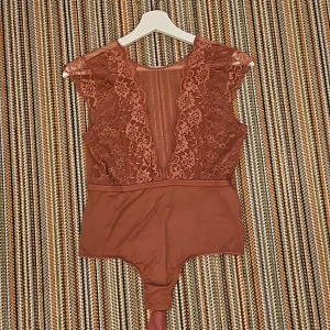 Body med spets  - En body med spets framför brösten och genomskinligt tyg mellan. Ryggen har en v öppning.