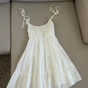 En fin vit klänning som knappt kommit till användning. Bra skick. Tunna släta band med möjlighet att knyta ut efter storlek. Ribbad där bak som gör att den sitter skönt i ryggen.