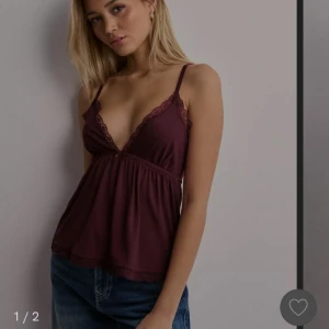 Lace Bow Top - V ringad topp i nyskick, lappen kvar och aldrig använd. Stretchig och mjuk i materialet. Smala axelband, spetskant vid bysten och nertill. Sedan även en dekorativ rosett mellan byst. Jätte fin topp och perfekt till sommaren till vardag eller fest. 