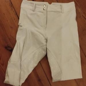 Vita zaczess byxor  - Vita snygga, sköna zaczess byxor säljes! De är använda runt 20 ggr och är i fint skick. Nypris 1200 kr, finns ej på hemsidan längre. Silver detaljer. Nötta i grenen (se bilder). Säljes pga köpt Ohio. Helskodda 