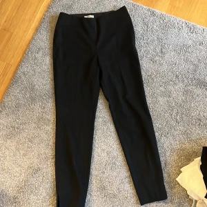 Kostymbyxor  - Svarta kostymbyxor med ett litet diskret blixtlås i sidan 