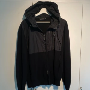 J.Lindeberg Cardigan Svart - Hej, säljer en sjukt snygg cardigan/hybridjacka från J.Lindeberg i helsvart. Använd men i dugligt skick. Storlek L. Enormt kvalitativ och lyxig, passar året runt i alla tillfällen. Nypris 3600kr. Pris kan diskuteras. Hör av dig vid intresse! 