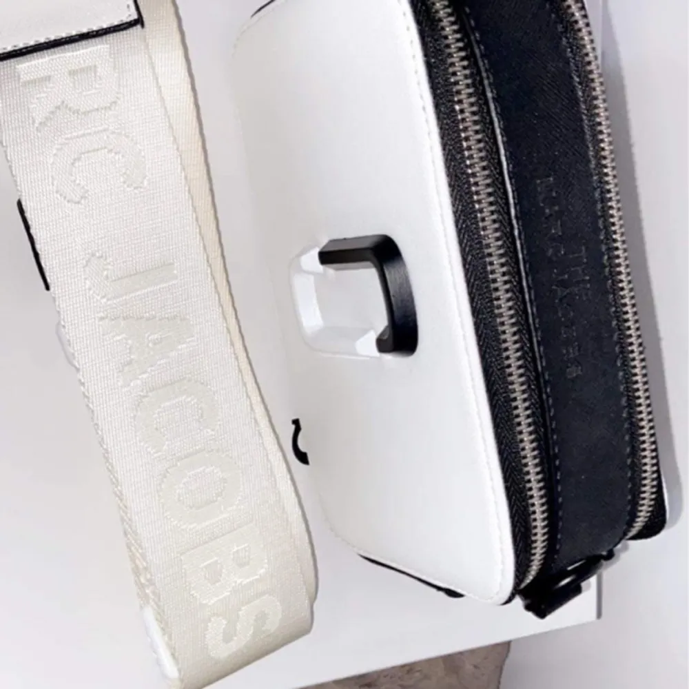 Har denna riktigt snygga Marc Jacobs väska obs ej äkta men i riktigt bra kvalitet ny oanvänd i svart o vit färg med ett brett justerbart band med loggan på . Accessoarer.