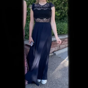 Balklänning - Anorlunda och cool mörkblå balklänning med svarta detaljer och spets. Köptes begagnad här på Plick. Liten reva i spetsen på ena sidan som är ihopsydd och är inget som syns. Storlek: 36 (petit). Jag är 164 cm lång och klänningen är uppsydd efter mig.