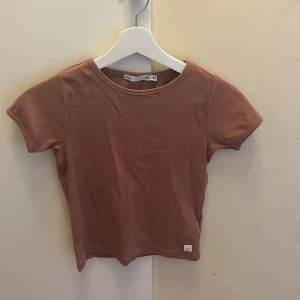 En rosa kortärmad tröja  - En lite mörkare gammaldags rosa tröja, Den är använd, Den är från lager 157