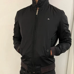 J.Lindeberg Jacka - Fodrad bomberjacka från J.Lindeberg. Svårmärkt litet hål längst ner vänster där bak, ena innerfickan har hål och en knapp sitter lite löst. Modellen är 183cm.  Funderingar samt prisförslag välkomnas! LIKNANDE PLAGG PÅ PROFILEN 7 