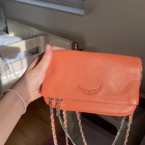 Zadig Voltaire väska - Säljer min jättefina oranga zadig väska då den inte kommer till så mycket användning (ca 4 ggr) köpt för ca 2500 kr och säljer då för 1300 kr men priset kan diskuteras💘