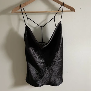 Topp/linne - Topp från Ginatricot i satinimitation med fina detaljer i ryggen. Aldrig använd. Toppen har dubbelt tyg fram. Ej reglerbara band. Storlek 36