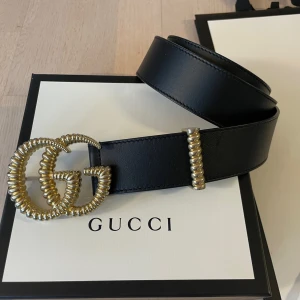 Gucci bälte Leather Belt Torchon Double G Buckle - Fantastiskt fint bälte från Gucci Leather Belt with torchon Double G buckle  Svart läder  Storlek 85 cm (Det finns tre hål som passar midjemått 83-88 cm) möjligheten finns att göra fler hål  Bredd 4 cm Spänne i guld metall ca 8x6 cm stor  Original ka