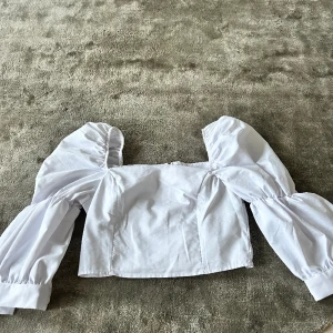 Vit croppad blus  - En vit croppad oanvänd blus med puffärmar. Enkel att stylea och perfekt till våren/sommaren. 