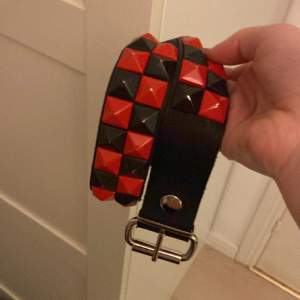 Ett bälte med nitar i svart och rött, använd typ 3 ggr max. 