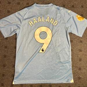 Oanvänd Manchester City Hemmatröja år 2023/24 i storlek M.  Namn på tröjan Haaland och nummer 9.