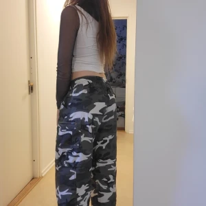 Y2K camo byxor - Inköpt mellan år 2000-2010. Supersnygga cargobyxor med camo-mönster. Äkta 2000-tal med två dragkedjor så de kan omvandlas till trekvartsbyxor eller shorts 😍. Tror det är L, men passar mig (S) samt även XS och M skulle jag tro. Svarar på alla frågor.