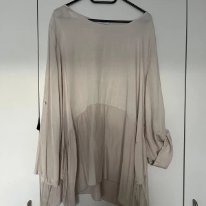 Blus silke - Beige blus one size i nyskick. Made in Italy. Ärmarna går att sätta upp, se höger sida.   Material: 100% viskos och detaljer i silke och rayon.   Mått: Längd ca 75 cm Byst ca 60 cm Midja ca 65 cm