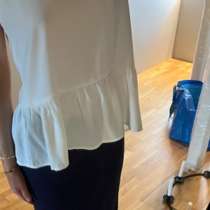 Vit tio med volang nertill - Jätte söt vit topp med en volang nertill, storlek s och passar perfekt till en kofta eller utan när de är varmt ute💗