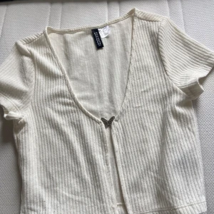 Vit top  - Vit top, har lite noppror på sig och man kan ha linne eller inget under ! Ganska bekväm också men fjärilen är bara prydnad så den går inte att stänga och öppna! 