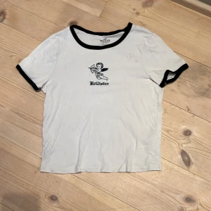 Hollister t-shirt - Vit t-shirt från Hollister med svarta detaljer. 100% bomull. Supersnygg o skön. Storlek M men liten i storleken, passar mig med XS o passar även S. Bra skick. OBS: ingen fläck, endast vattenstänk (bild 5). KOLLA MIN PROFIL💞